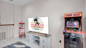 A living room with a flat-screen TV, a popcorn machine, and an arcade game machine.