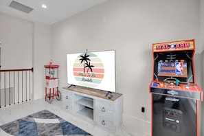 A living room with a flat-screen TV, a popcorn machine, and an arcade game machine.