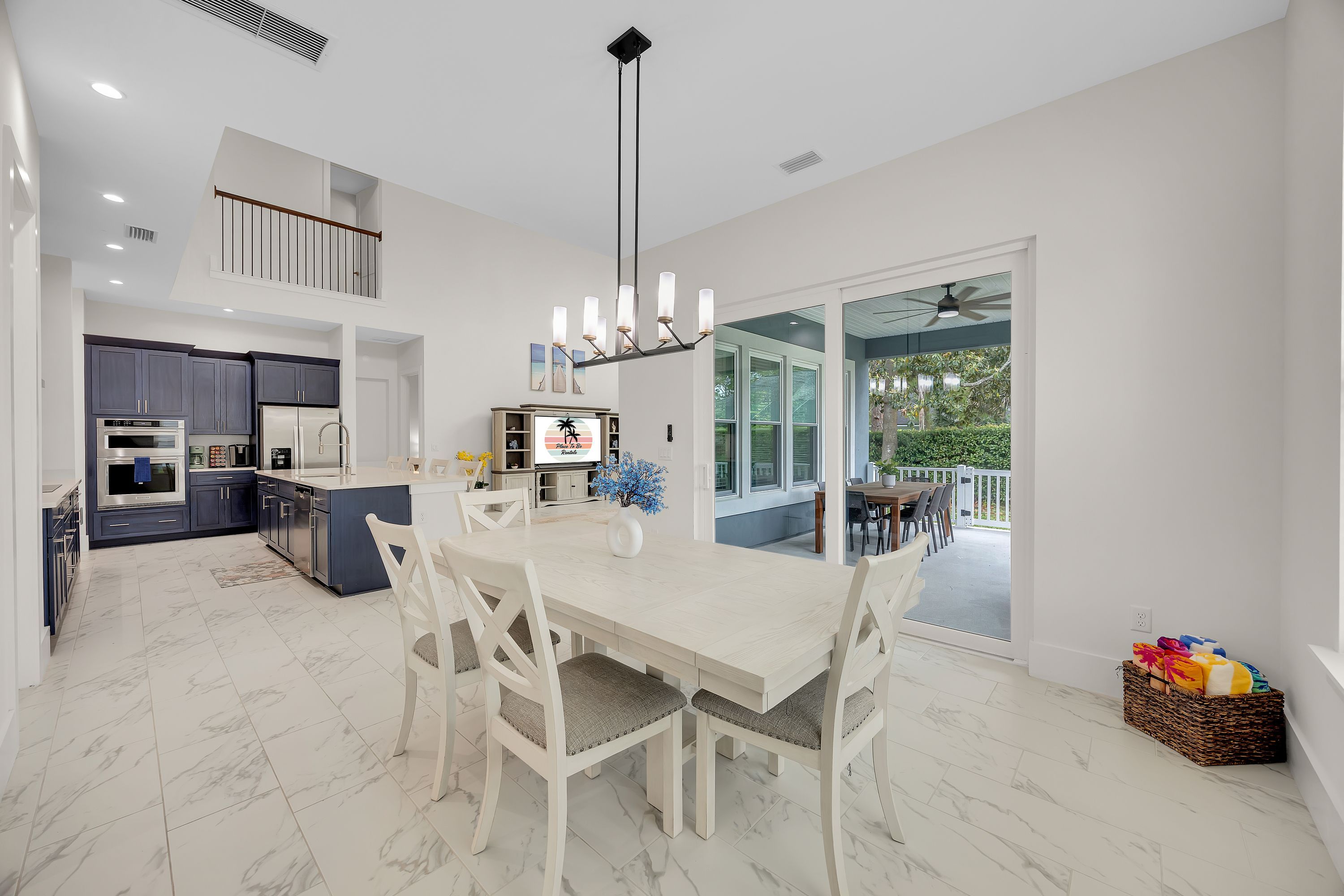 Una cocina moderna con armarios oscuros, una isla central y una zona de comedor con mesa y sillas blancas.