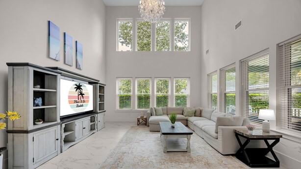 A spacious living room with a large flat-screen TV, a sofa set, a coffee table, and a chandelier. - Salt Air 6BR Game Room Walk to Beach Luxe (Ponte Vedra Beach)