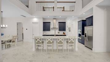 A spacious kitchen with a central island, modern appliances, and a dining area with white furniture.