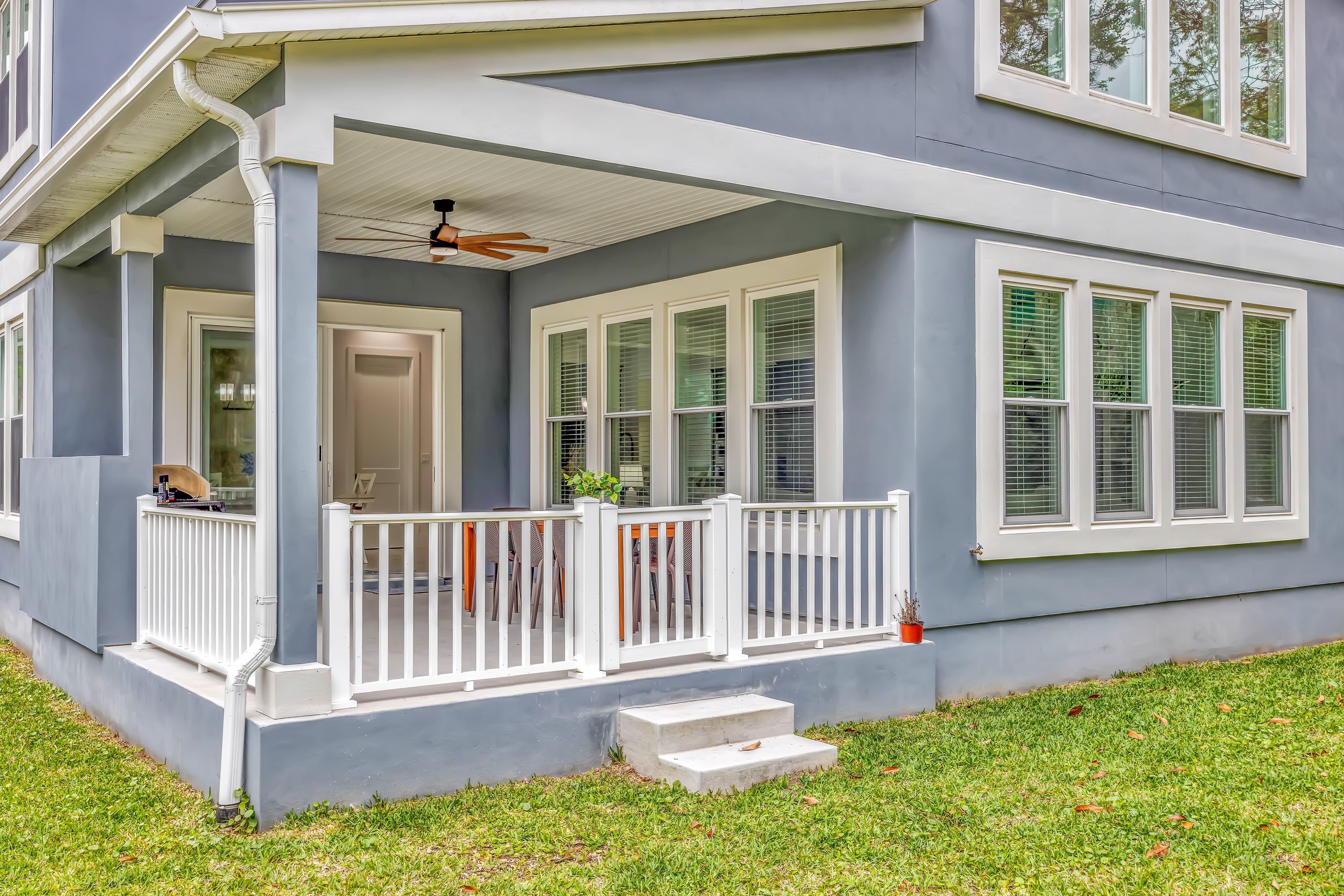 A house with a covered porch, multiple windows, and a small set of steps leading to the entrance.
