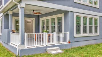 A house with a covered porch, multiple windows, and a small set of steps leading to the entrance.