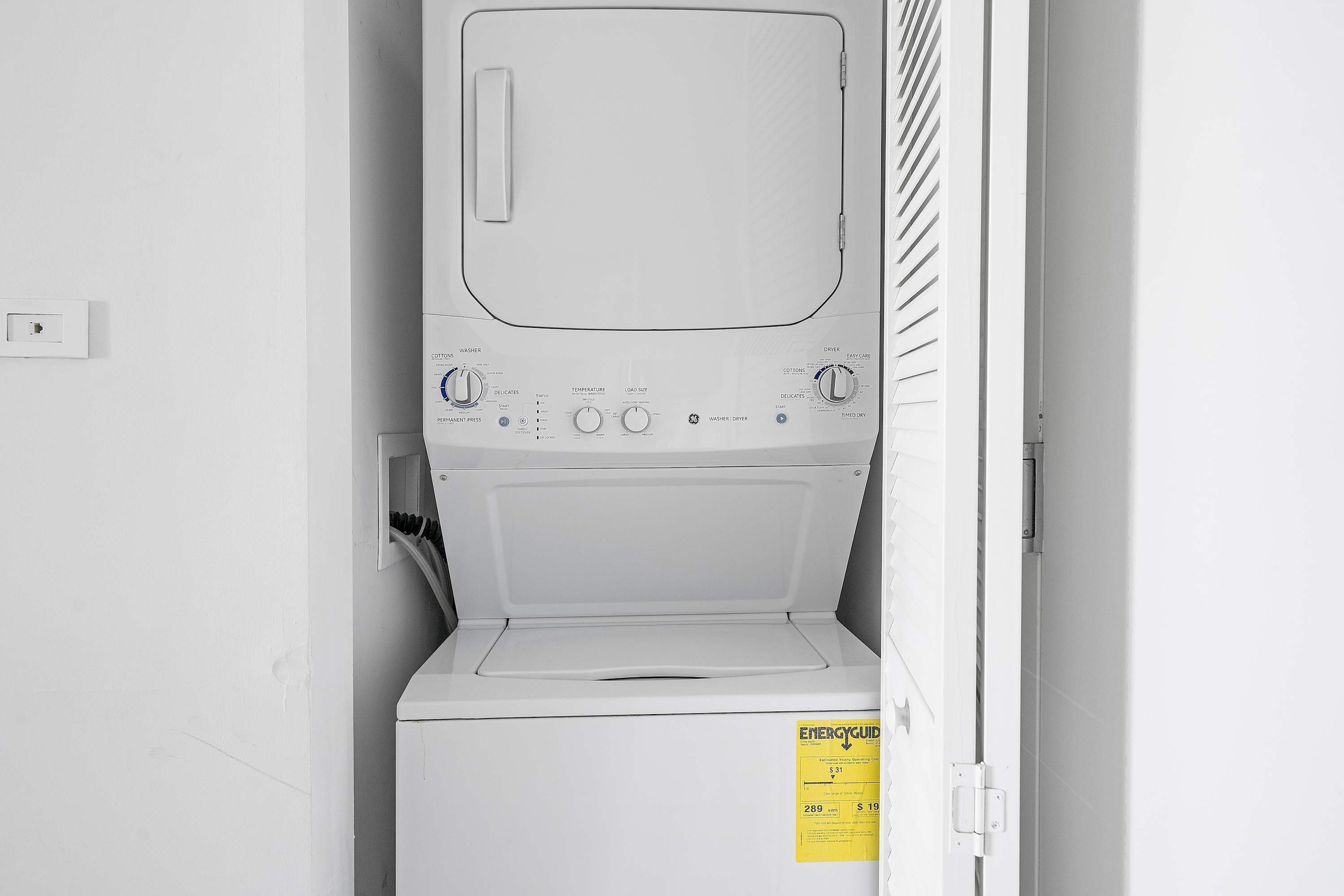 A compact, white, front-loading washing machine with a control panel featuring multiple settings and a yellow energy efficiency label.