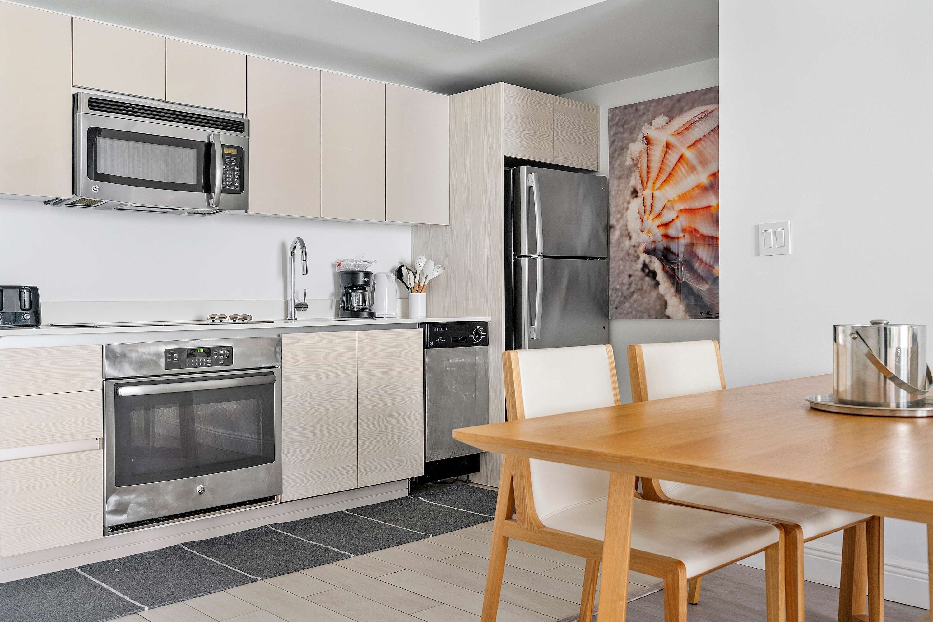 A modern kitchen with stainless steel appliances, a dining table, and chairs.