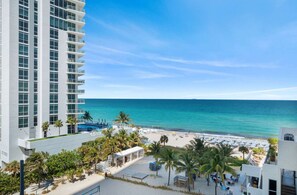 A high-rise hotel with a beach view, including a pool area and outdoor seating. - Beachfront Condo Front Oceanview Balcony and Pools (Hollywood)