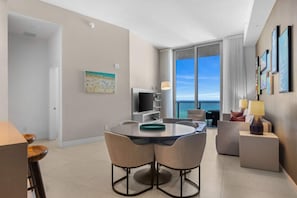 A modern hotel room with a dining area, a TV, and a balcony with a view. - Beachfront Condo Front Oceanview Balcony and Pools (Hollywood)