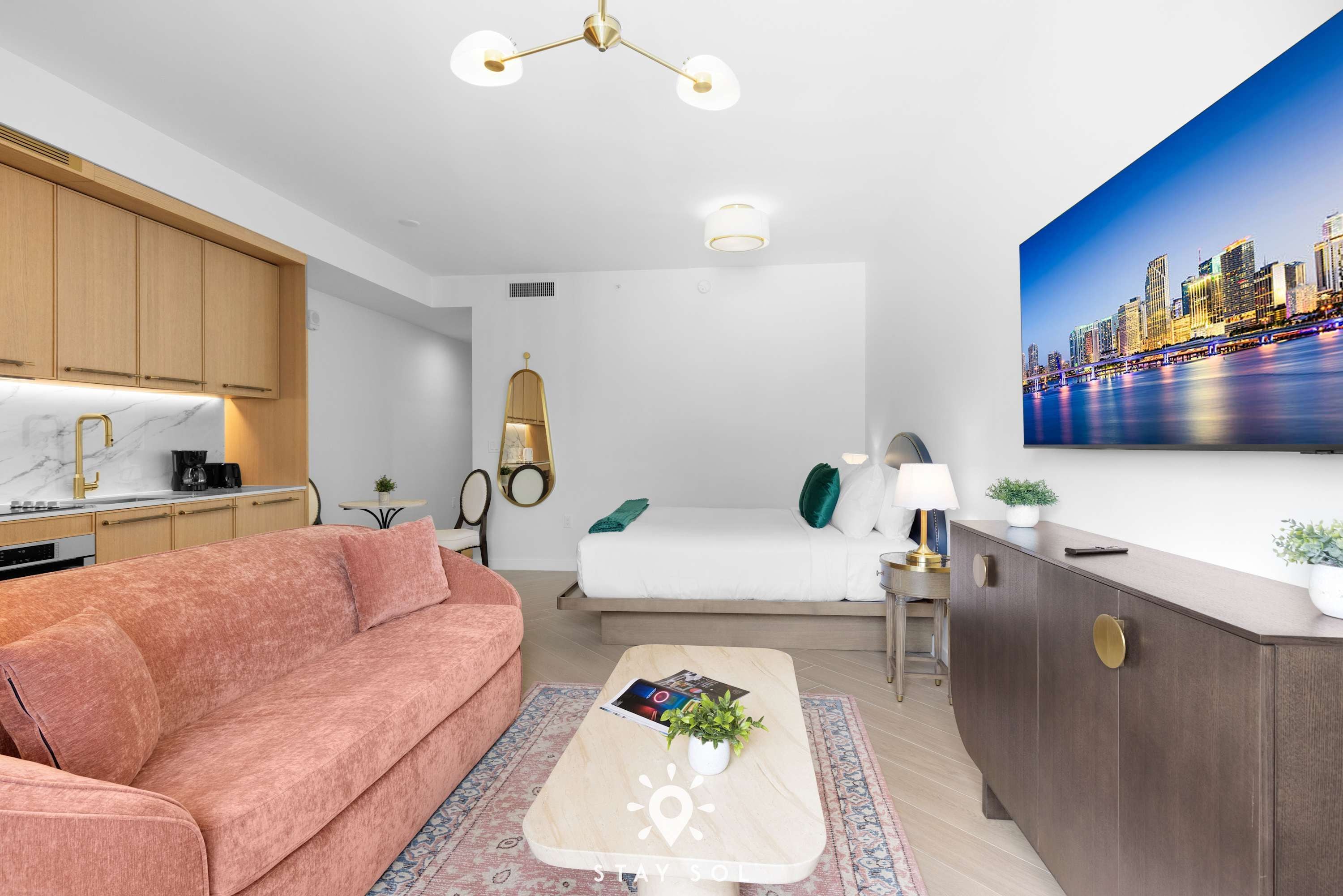 Ett modernt hotellrum med en soffa, ett soffbord, ett skrivbord och en tavla med en stadsbild på väggen.