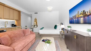 Et moderne hotelværelse med sofa, sofabord, skrivebord og et bybillede på væggen.