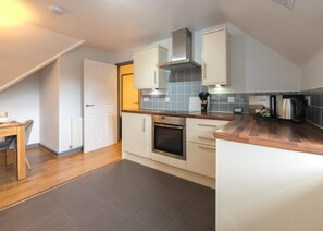 A compact kitchen with a built-in oven, a stove, and a coffee maker on the counter. - New 1 Bedroom Apartment With Free Parking (Southampton)