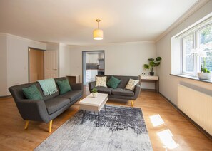 A modern living room with two sofas, a coffee table, and a large window. - Brand New 2 Bedroom Apartment Free Parking (Southampton)