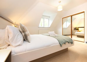 A bedroom with a large bed, a mirror, and a view of another room. - Brand New 2 Bedroom Apartment Free Parking (Southampton)