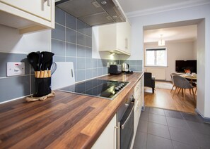 A modern kitchen with a wooden countertop, built-in oven, and a dining area with a chair and table.