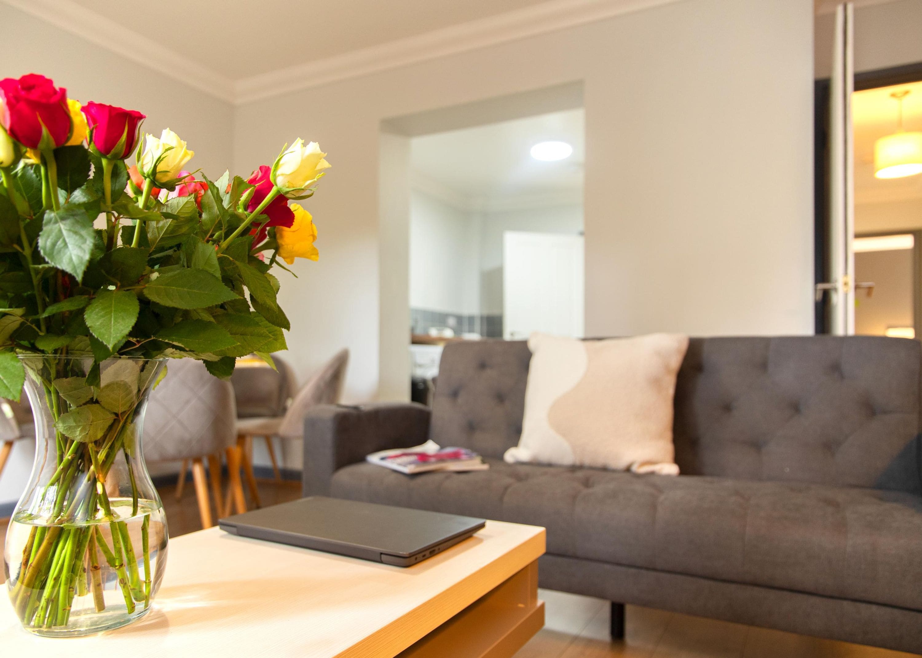 A living room with a grey sofa, a wooden coffee table, and a vase with flowers.