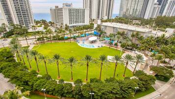 A high-rise hotel with a central courtyard surrounded by palm trees and a swimming pool.