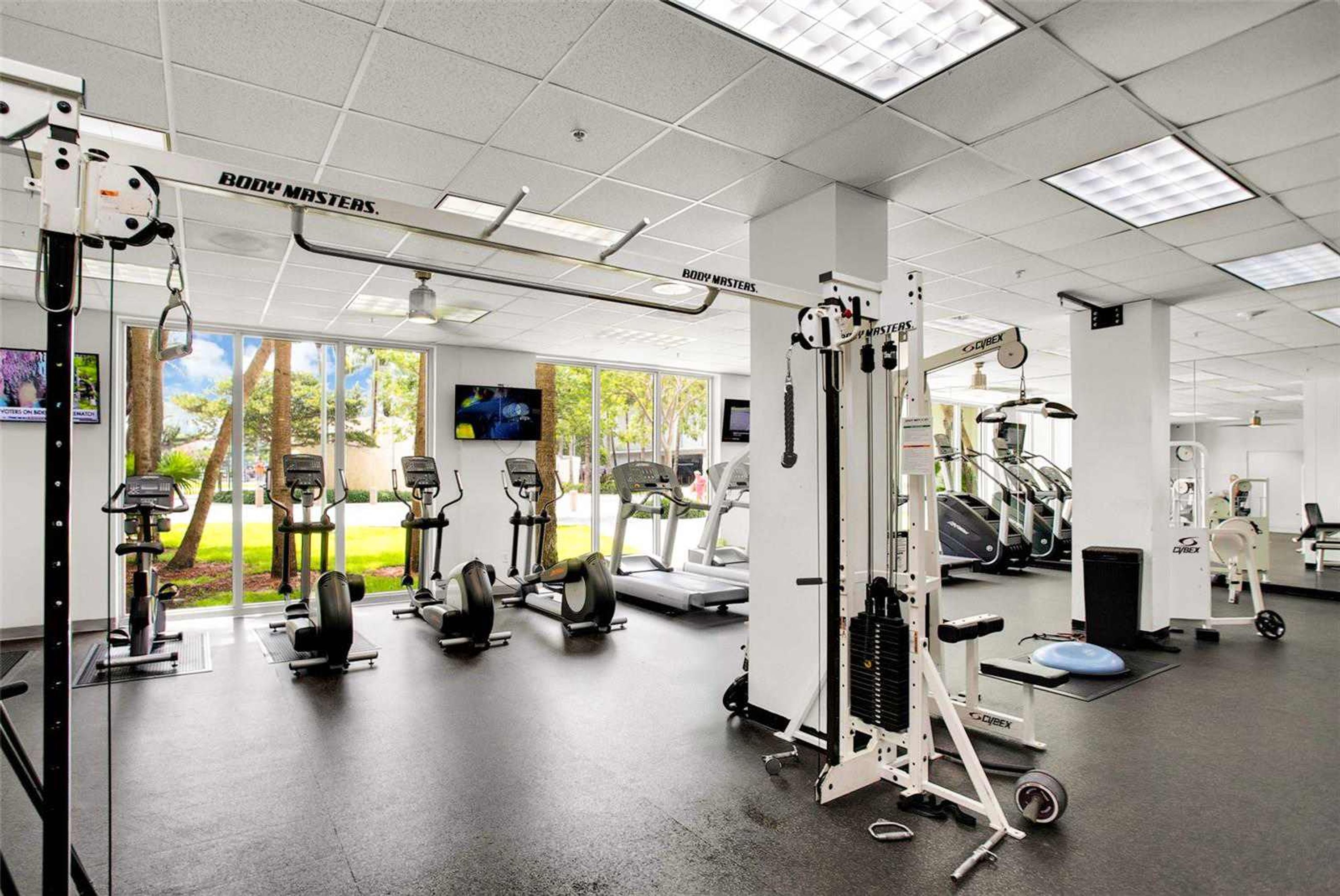 Ein Fitnessstudio mit verschiedenen Trainingsgeräten, darunter Laufbänder, Kraftgeräte und ein Rudergerät.