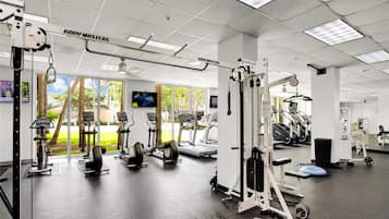 A gym with various exercise equipment, including treadmills, weight machines, and a rowing machine.