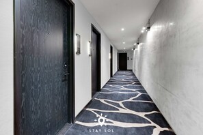 A hotel corridor with patterned carpet, doors, and wall-mounted light fixtures. - High Design Studio Miami Pulse E11even (Miami)