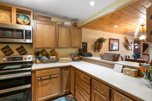 A kitchen with wooden cabinets, stainless steel appliances, and various kitchenware. - Skycrest 1721 - Big Sky (Big Sky)