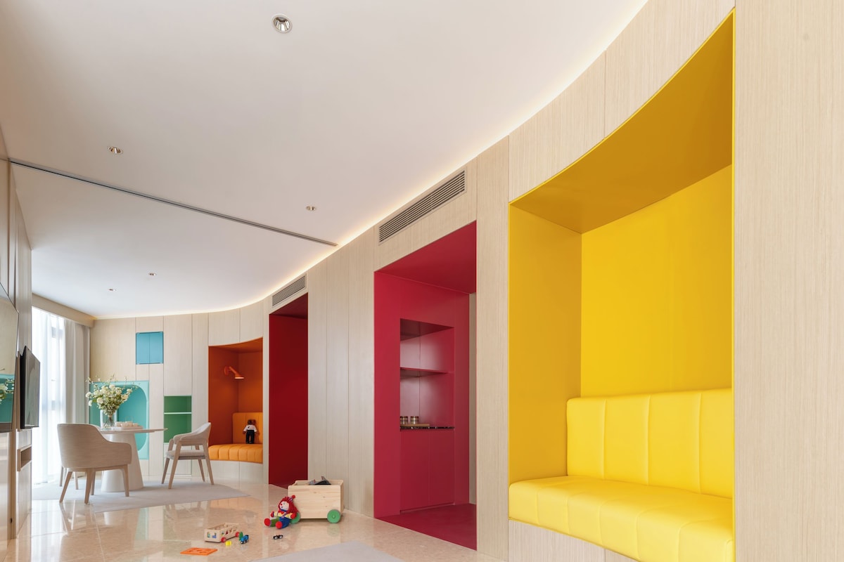 Un interior moderno con techo curvo, sofá amarillo y zona de juegos roja.
