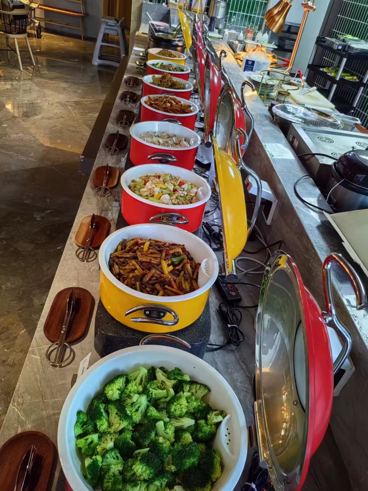 A buffet line with various dishes in large bowls and pots, a sink, and a stove.