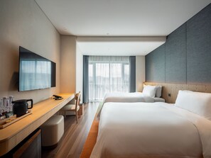 A hotel room with a flat-screen TV, a desk with a kettle, two beds, and a large window with curtains. - Jingju Hotel Shenzhen (Shenzhen)