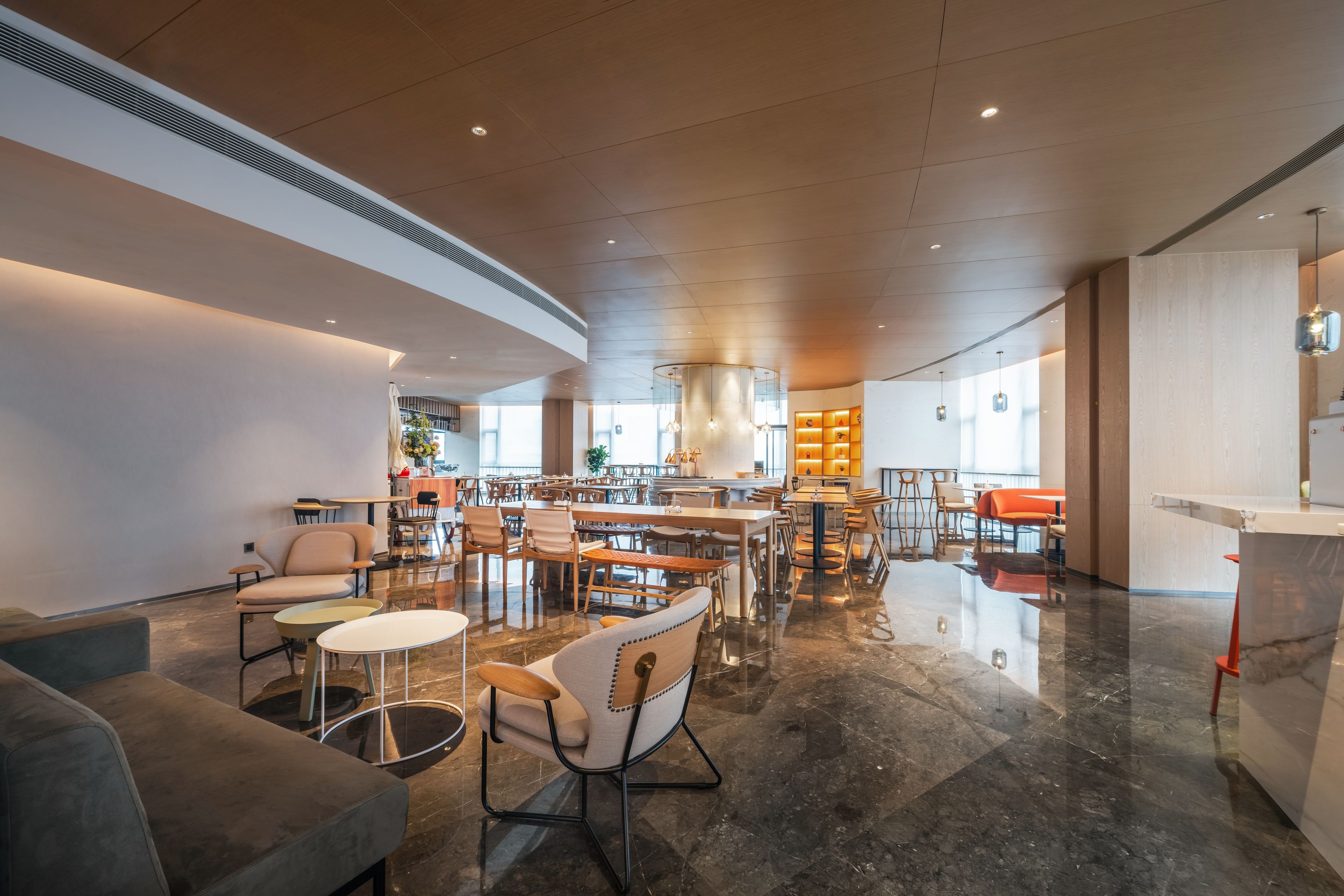 A spacious hotel lobby with a central bar area, multiple seating arrangements, and a modern design.