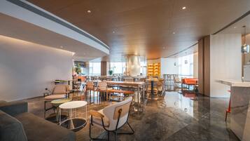 A spacious hotel lobby with a central bar area, multiple seating arrangements, and a modern design.