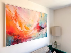 A room with a large abstract painting on the wall, a floor lamp, and a green upholstered sofa. - Derby City Centre Apt | Free Parking | Long Stays (Derby)