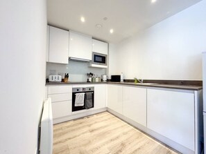 A modern kitchen with white cabinets, a microwave, a toaster, and a built-in oven. - Derby City Centre Apt | Free Parking | Long Stays (Derby)
