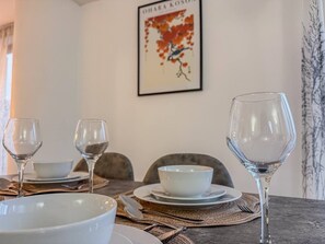 A dining table set with plates, bowls, and wine glasses, with a framed artwork on the wall behind. - Stylish 2BR Apt | Jewellery Quarter + Free Parking (Birmingham)