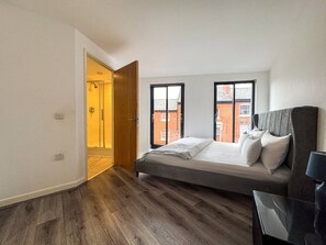Ein Schlafzimmer mit einem Bett, einem Nachttisch, einem Fenster und einer Tür zu einem Badezimmer.