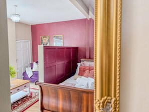 A bedroom with a wooden bed, a red accent wall, and a white door. - Central Stratford Retreat | Town Centre (Warwickshire)