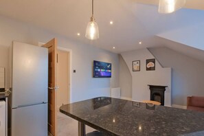 Una cocina moderna con encimera de granito, horno empotrado y televisor fijado a la pared.
