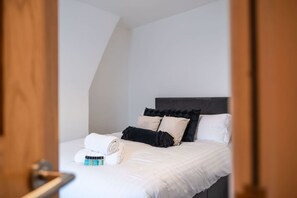 A bedroom with a bed, pillows, and a rolled towel. - Central 1 Bed | Prime Stratford Town Centre (Stratford-upon-Avon)