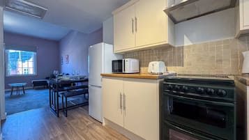 A compact kitchen with a stove, microwave, and cabinets.