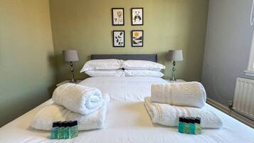 A hotel room with a large bed, two bedside tables with lamps, a radiator, and artwork on the wall.