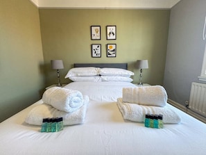 Een hotelkamer met een groot bed, twee nachtkastjes met lampen, een radiator en een kunstwerk aan de muur.