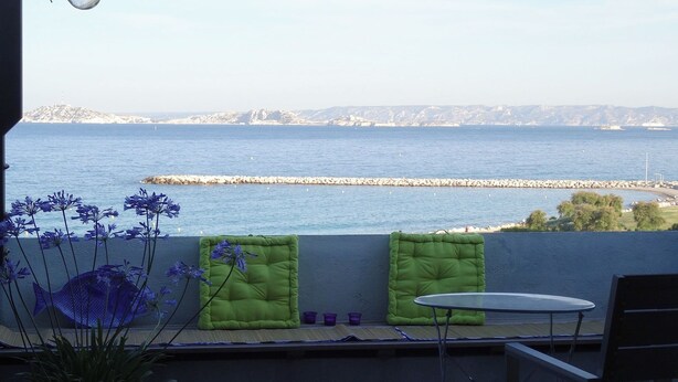 Ein Balkon mit Meerblick, einem Stuhl, einem kleinen Tisch und einem Blumentopf.