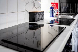 Une cuisine avec un plan de travail noir, un évier et une pile de boîtes noires posées sur le plan de travail.