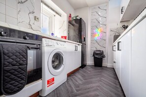 Une buanderie équipée d’un lave-linge, d’un sèche-linge et d’une poubelle.