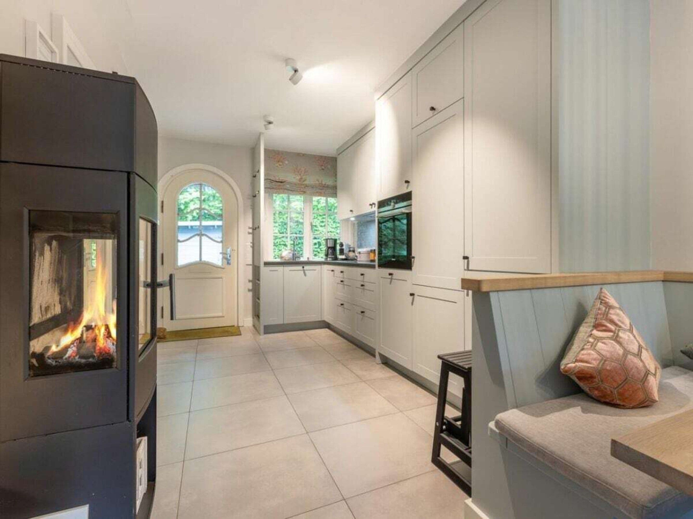 A modern kitchen with white cabinets, a built-in stove, and a view of the outdoors through a window.