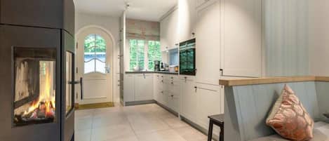 A modern kitchen with white cabinets, a built-in stove, and a view of the outdoors through a window.