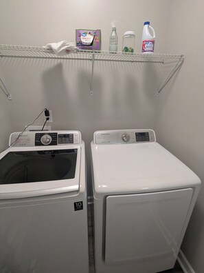 A laundry area with two washing machines, a shelf with cleaning supplies, and a power outlet. - Private 3-bedroom house with Hot Tub near White Water Center and Belmont (Mount Holly)