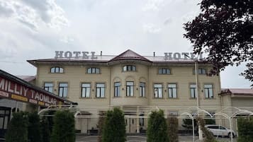 Un hotel con fachada simétrica, varios ventanales y una entrada central.