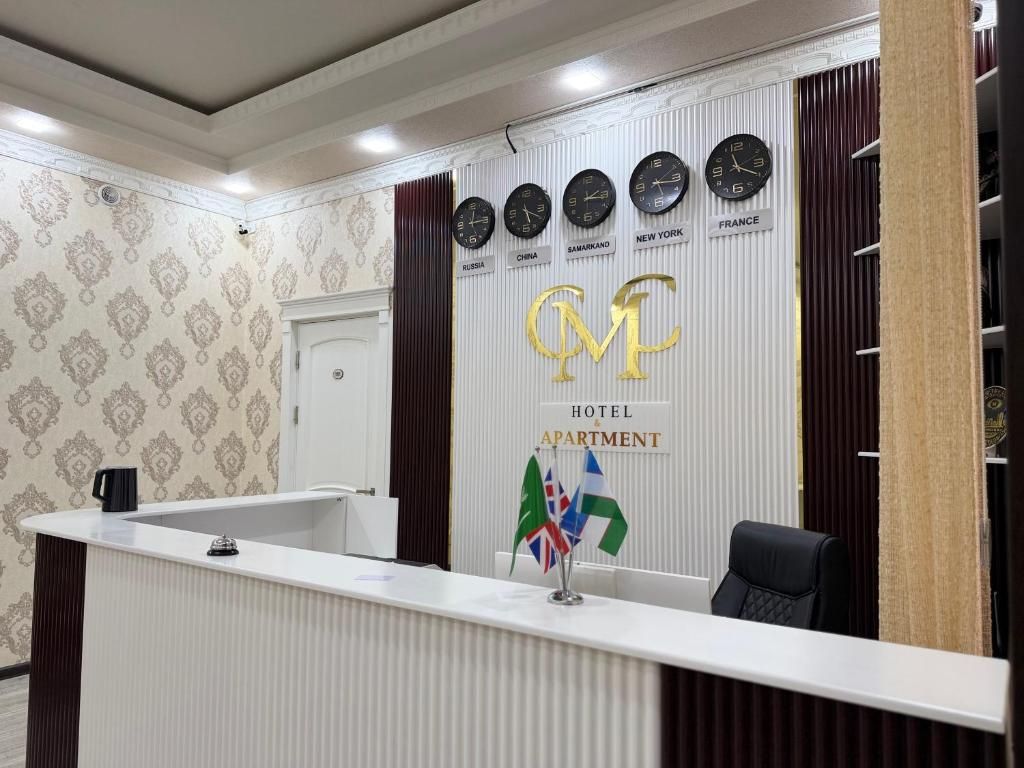 A hotel reception desk with clocks displaying different time zones, a sign indicating the hotel and apartment services, and a flag display.
