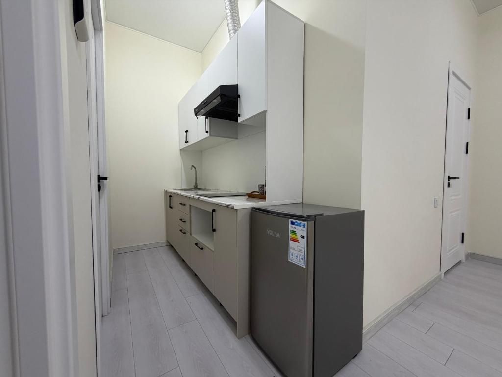 Una cocina compacta con refrigerador integrado, un lavamanos y armarios.