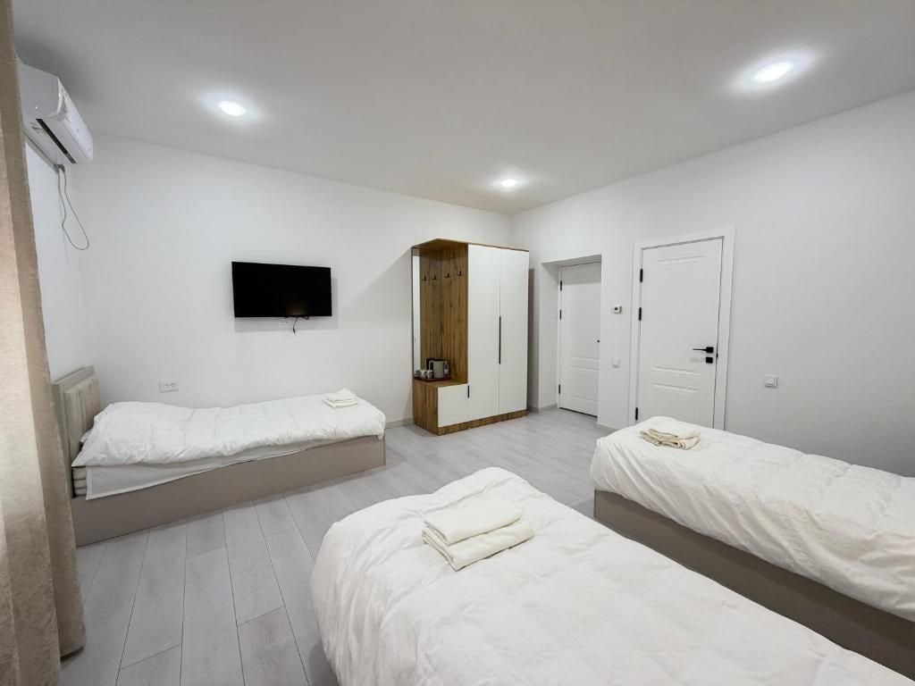 Quarto de hotel com duas camas de solteiro, um guarda-roupa, uma televisão e uma porta.