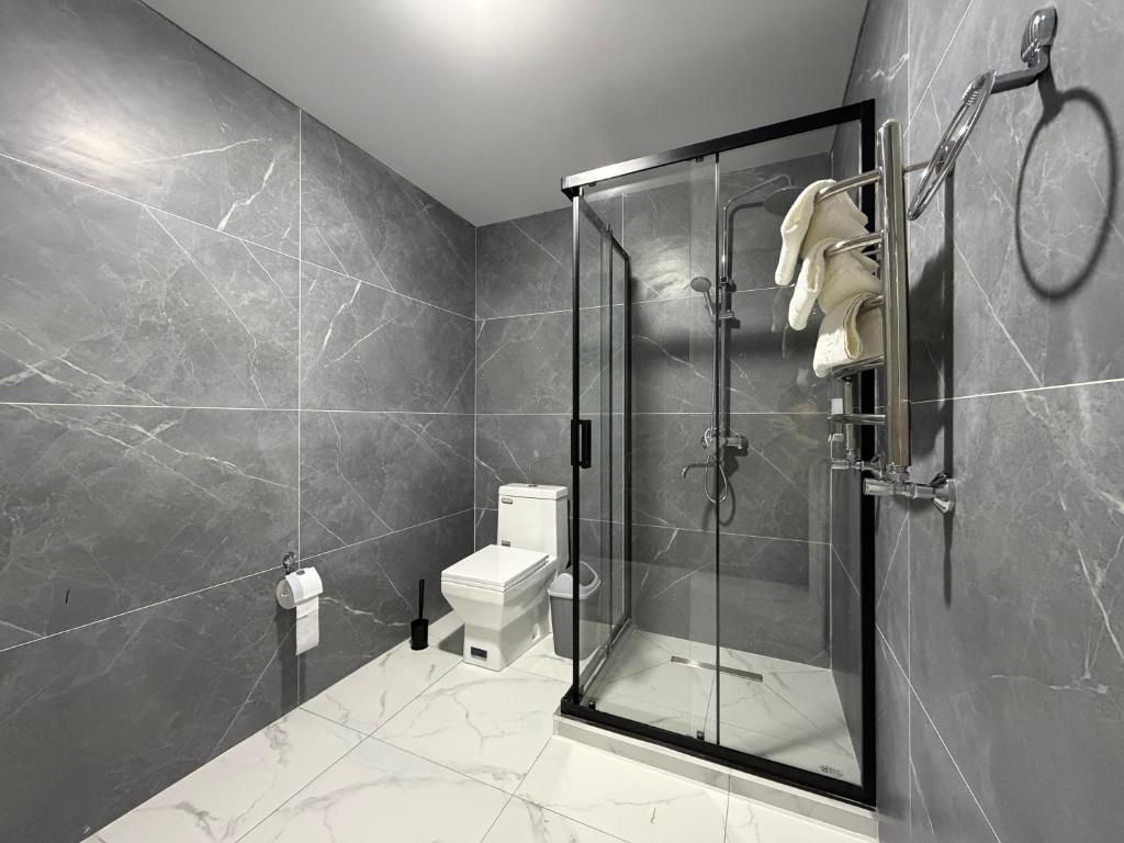 Un baño moderno con ducha envuelta en vidrio, inodoro y barra para toallas.