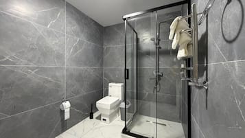 Un baño moderno con ducha envuelta en vidrio, inodoro y barra para toallas.